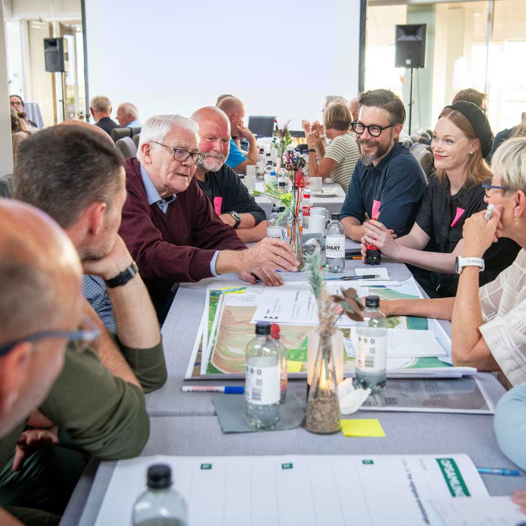 Folk der sidder sammen ved et bord og taler