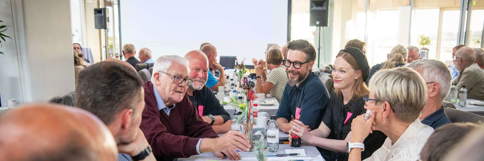 Folk der sidder sammen ved et bord og taler