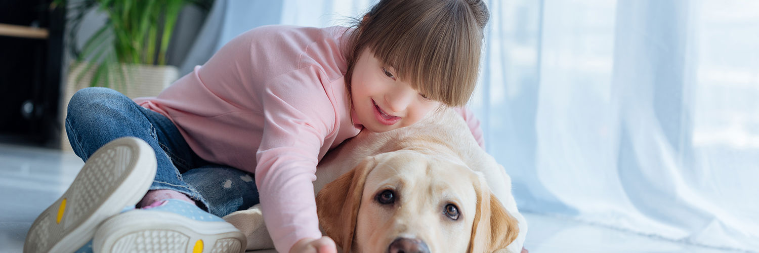 Handicappet pige der ligger på gulvet sammen med hendes hund