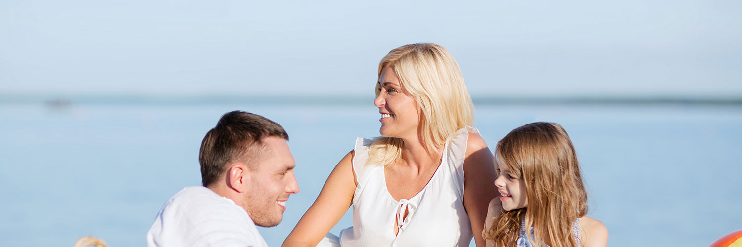 Far, mor og datter der ligger på stranden