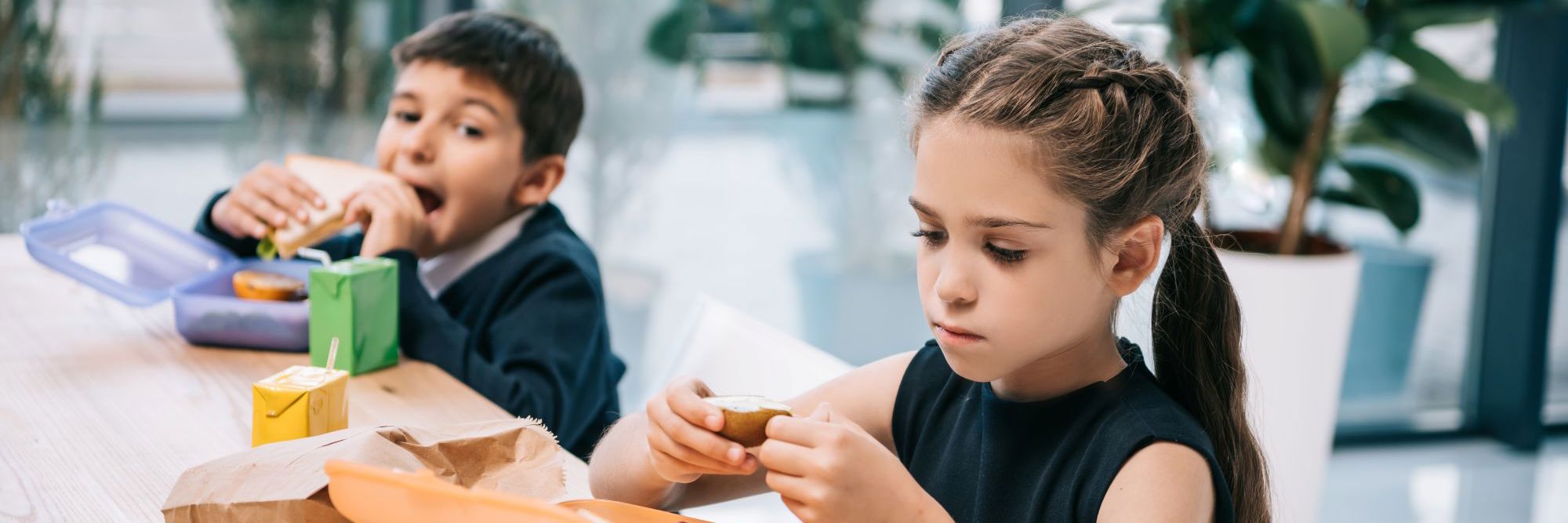 Dreng og pige i skolealderen spiser madpakker