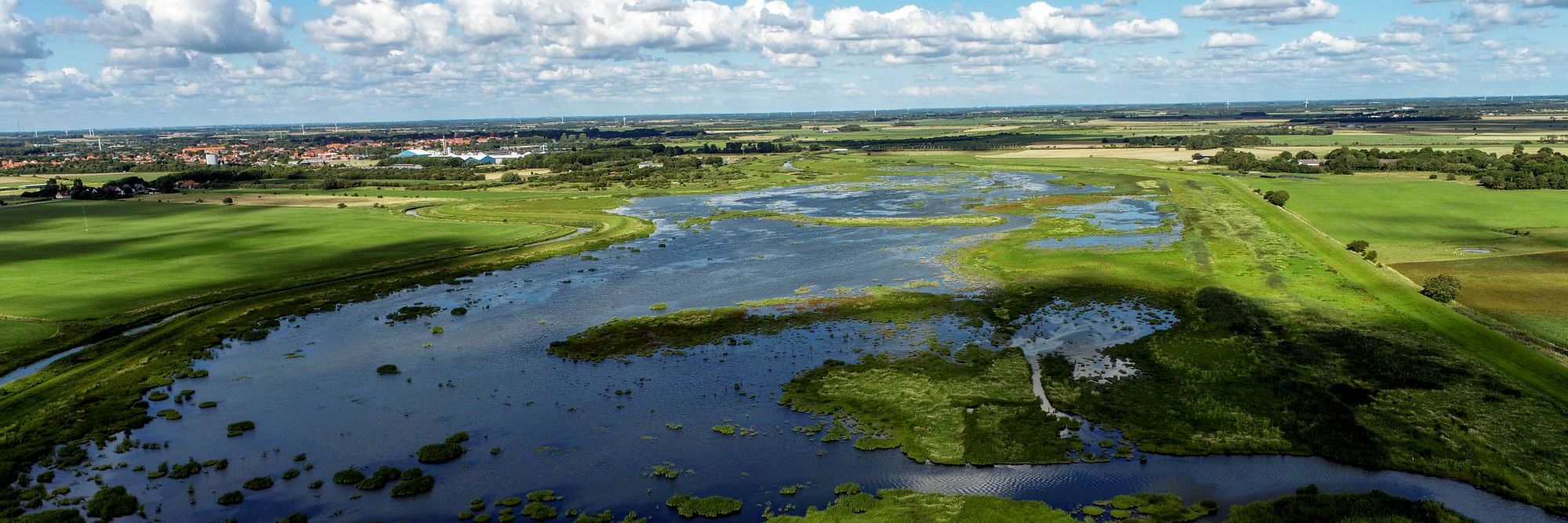 Dronebillede af en sø med grøn natur omkring