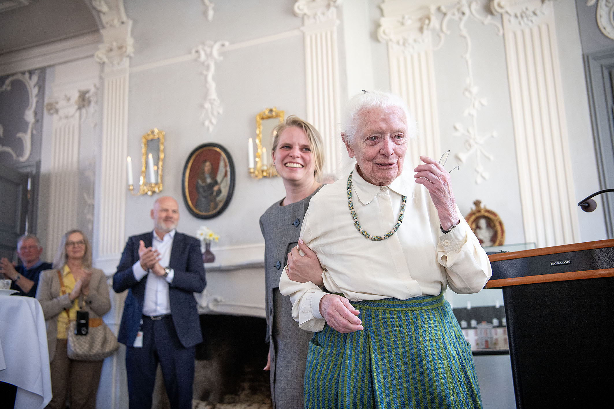Hanne Vedel er rørt og får en hjælpende hånd af sit barnebarn mens folk klapper.