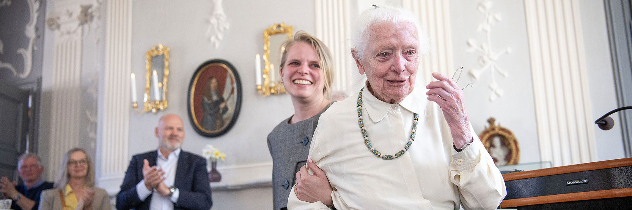 Hanne Vedel er rørt og får en hjælpende hånd af sit barnebarn mens folk klapper.