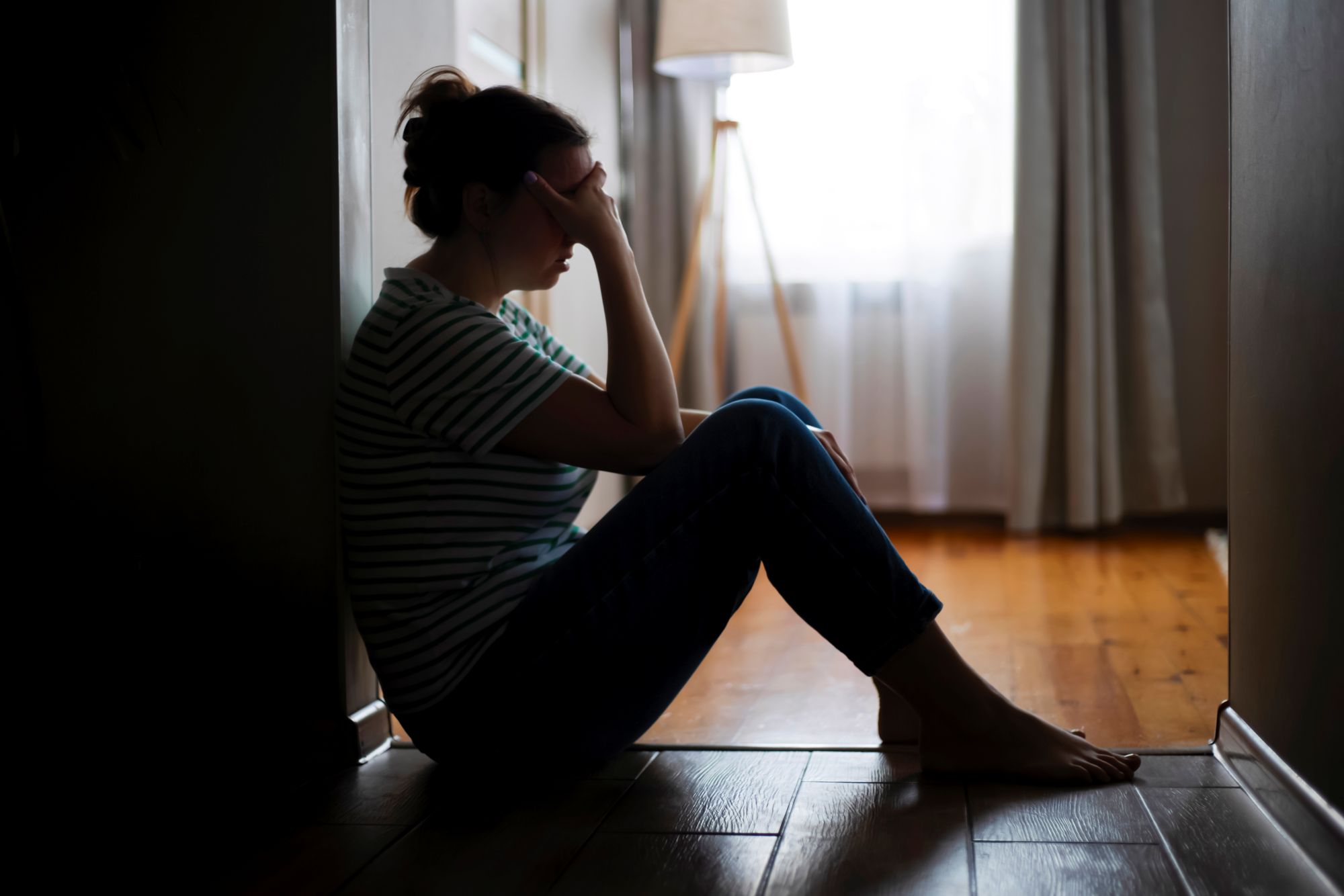Kvinde sidder i mørke og ser trist ud