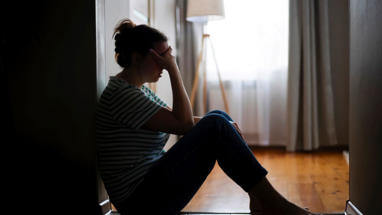 Kvinde sidder i mørke og ser trist ud
