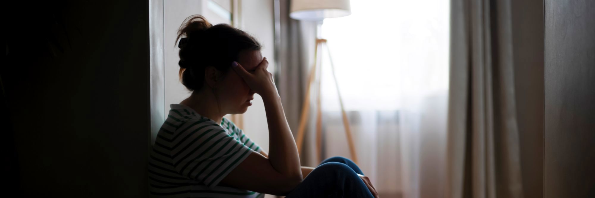 Kvinde sidder i mørke og ser trist ud