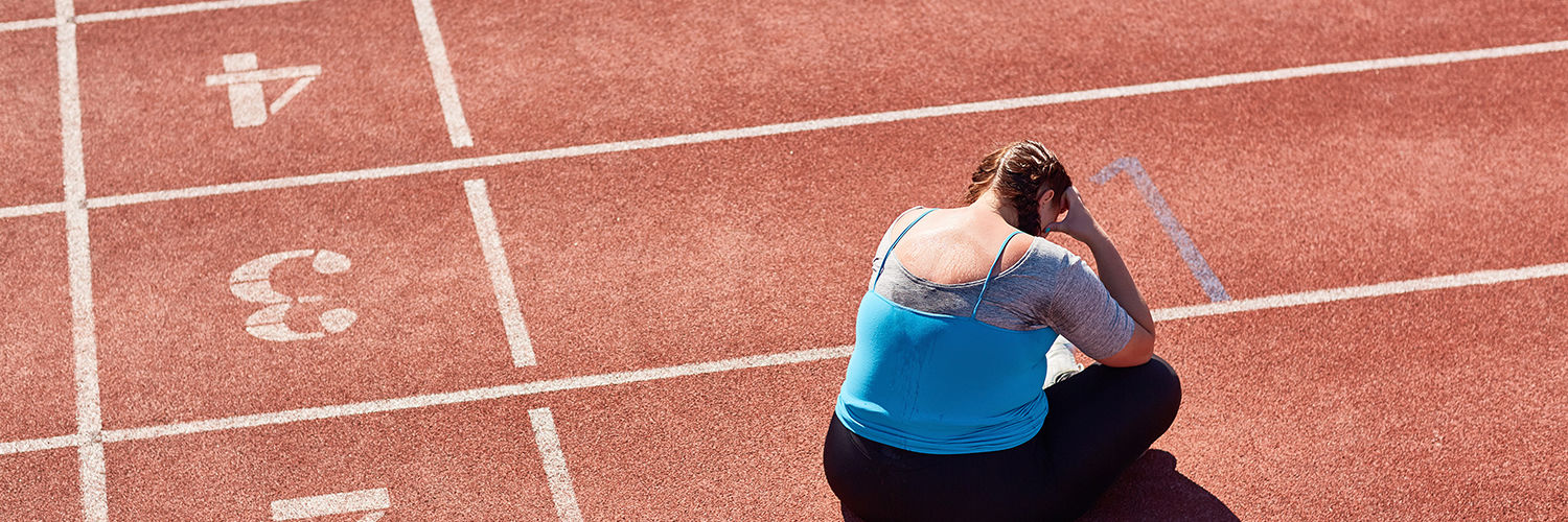 Frustreret kraftig pige der sidder på en løbebane