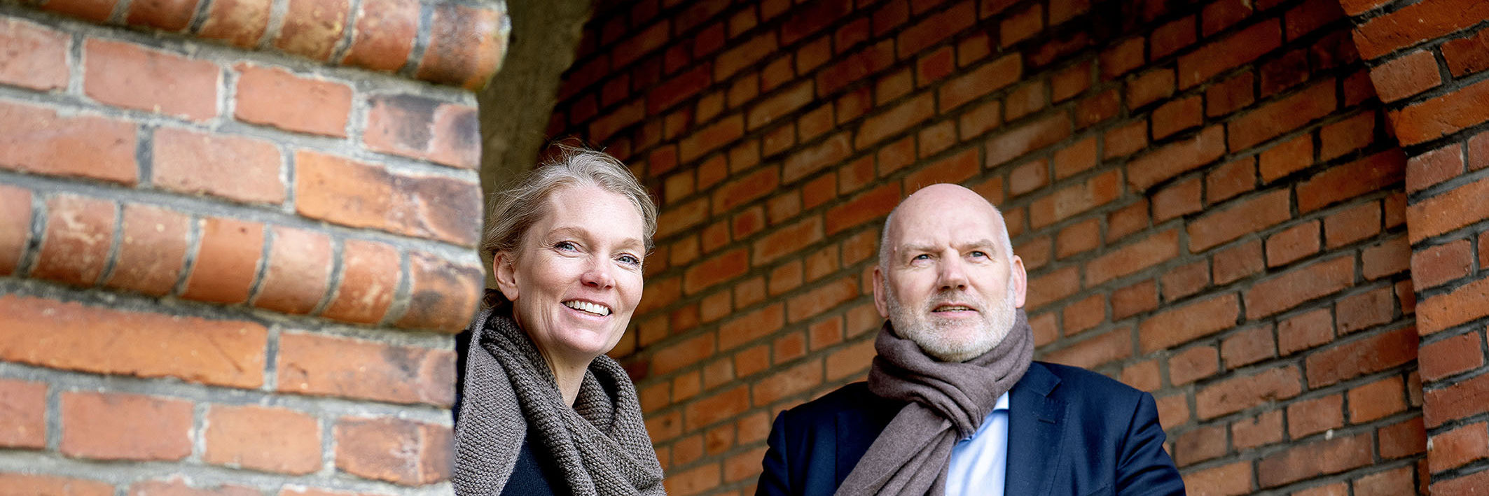 Kvinde smiler og mand kigger ud i horisonten.