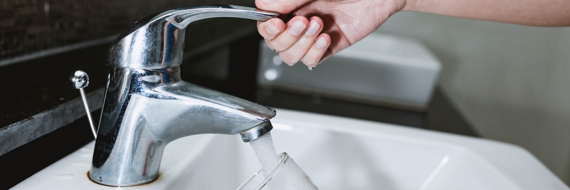 Person tager vand fra en vandhane