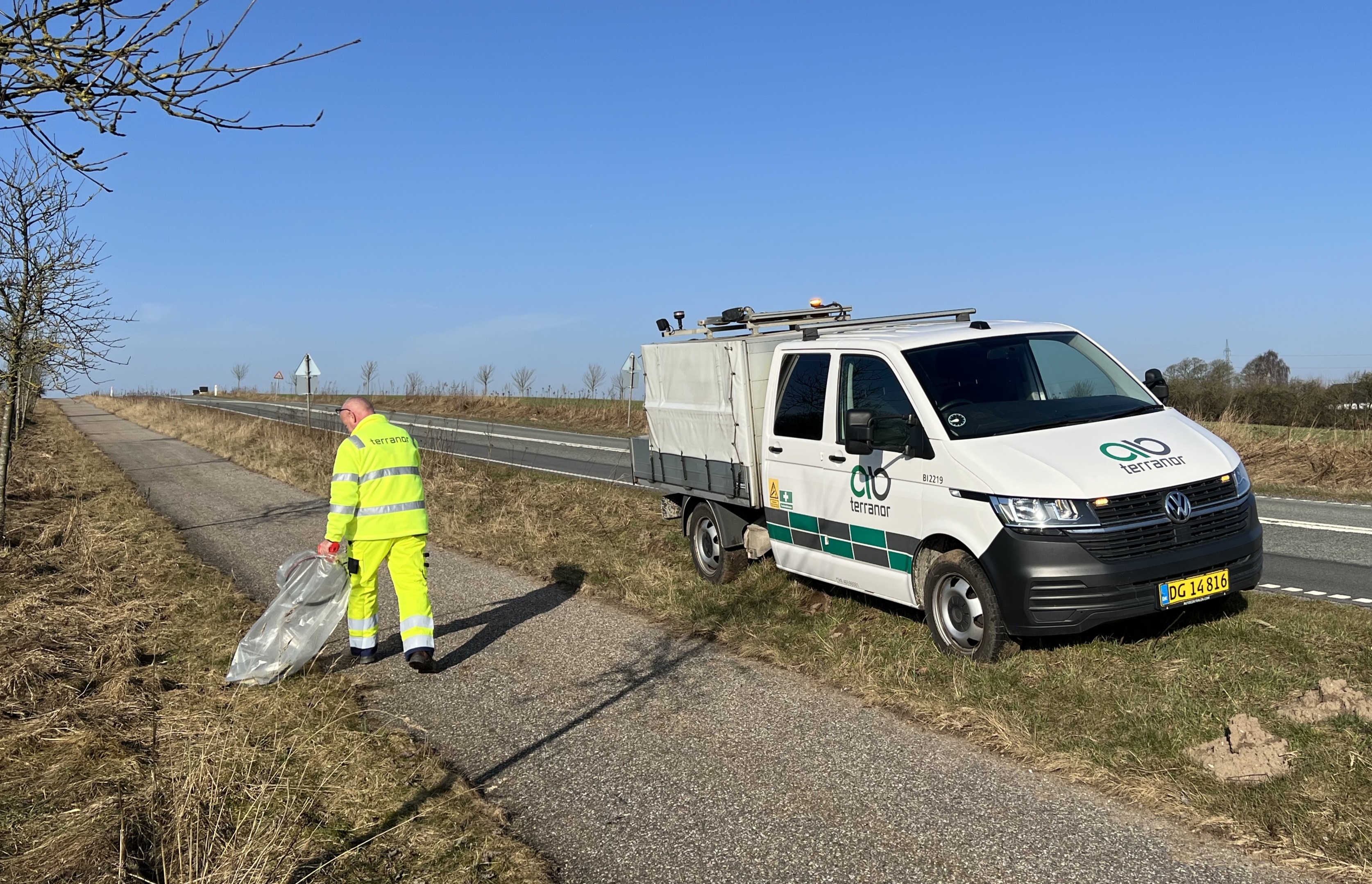 Mand samler affald i grøftekant