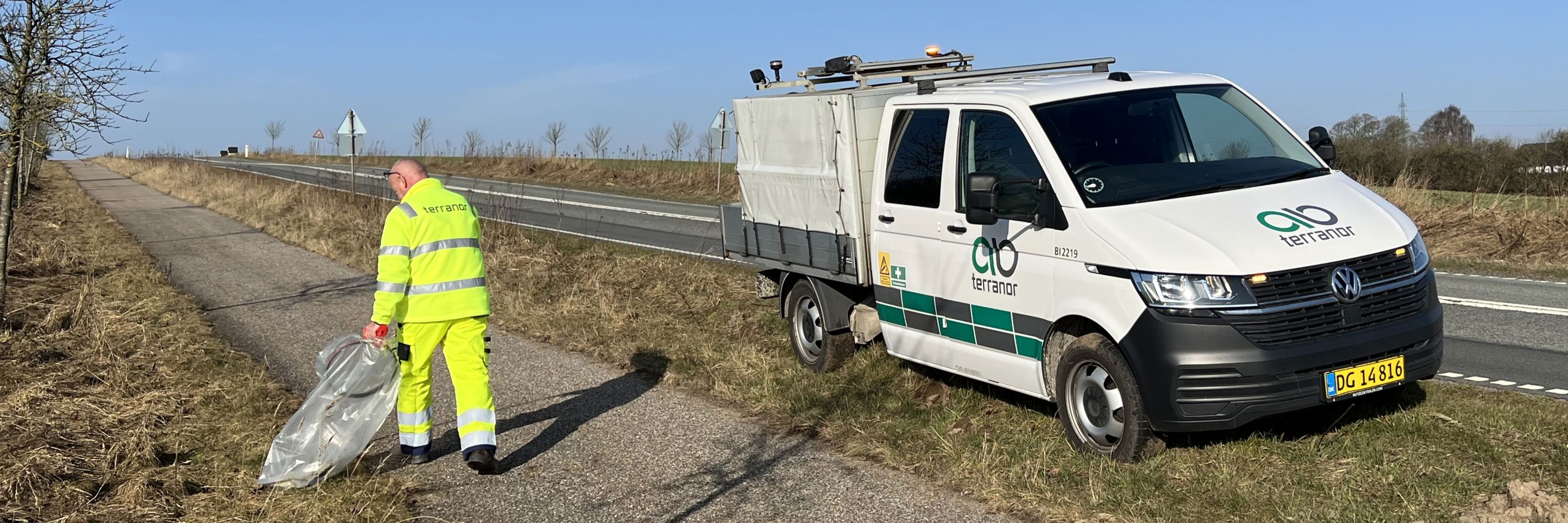 Mand samler affald i grøftekant