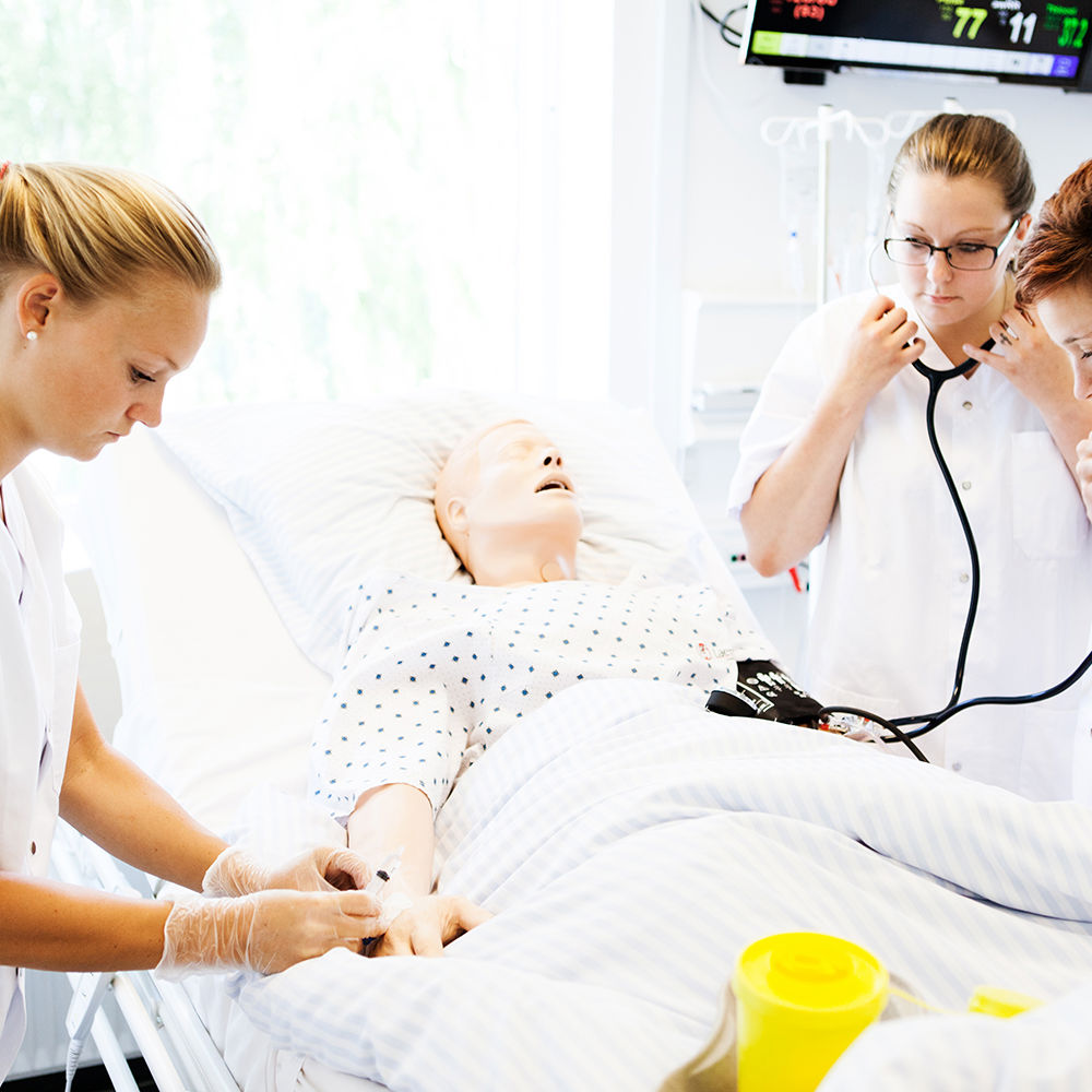 Tre social- og sundhedsassistenter øver sig på figurant i sengen