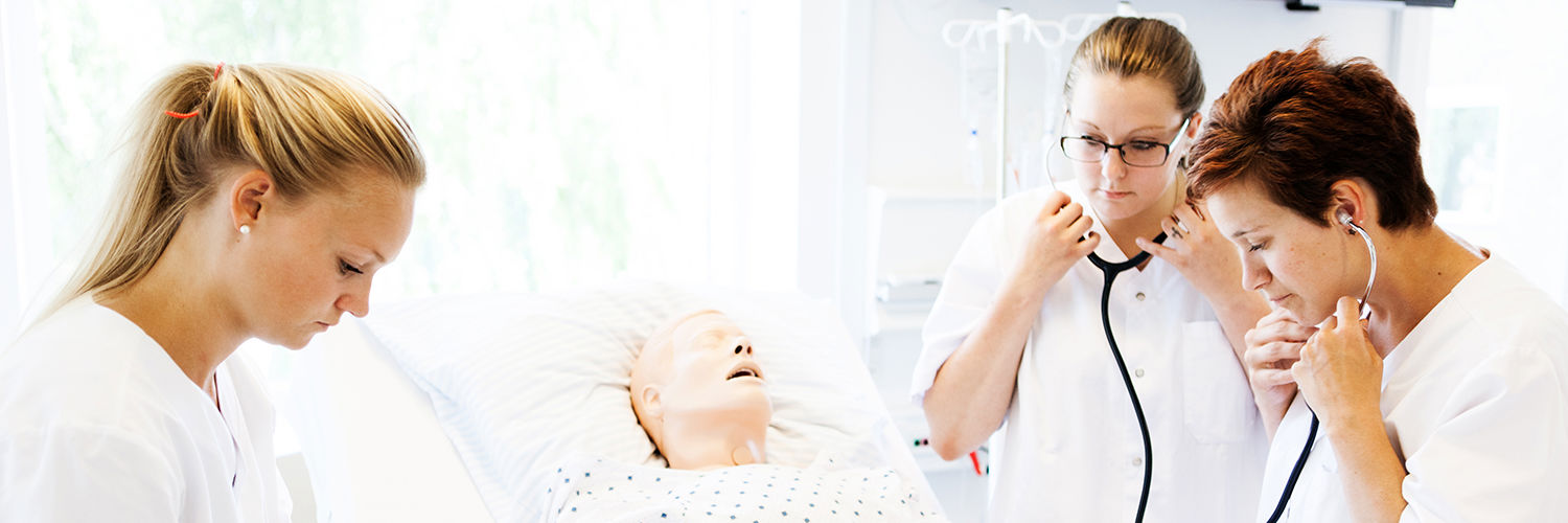 Tre social- og sundhedsassistenter øver sig på figurant i sengen